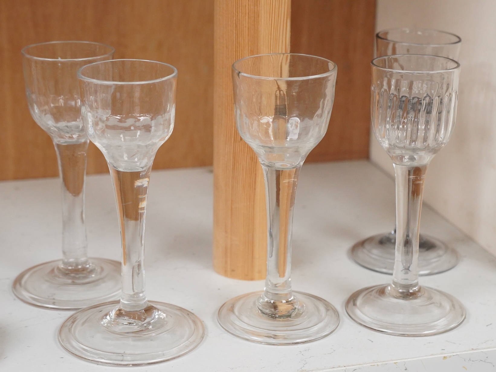 Five 18th century cordial glasses, in lead and soda glass, with fluted bowls, columnar stems, on domed and folded feet, 13.5cm high